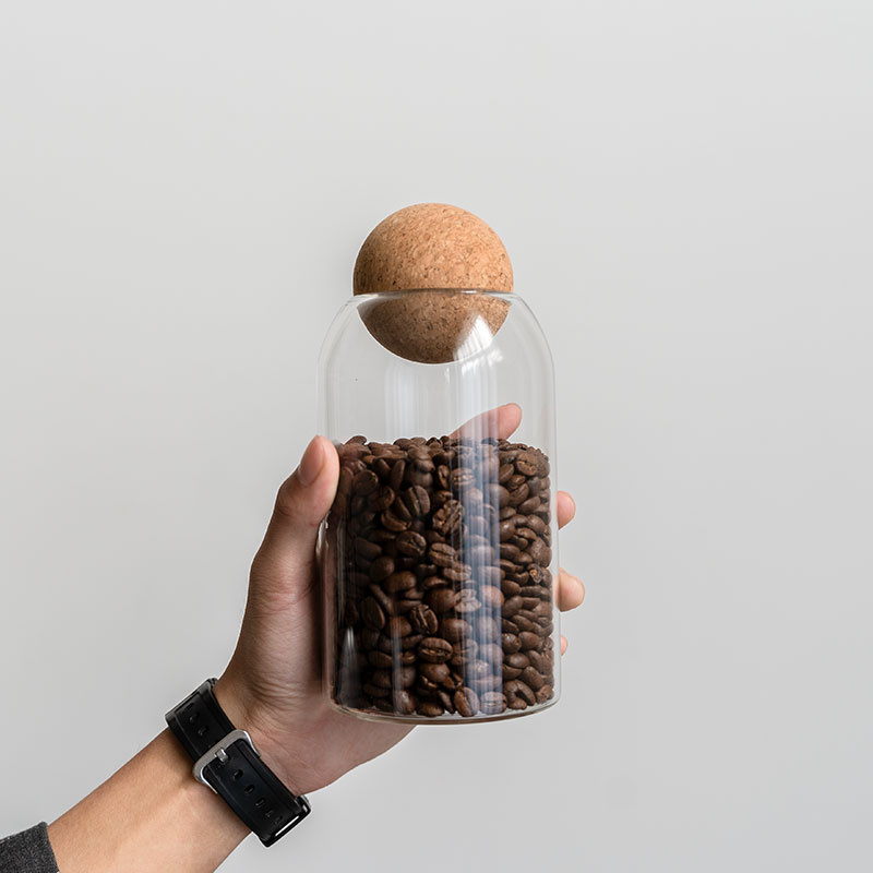 Cork lid lifted from a jar of coffee beans, ready to scoop
